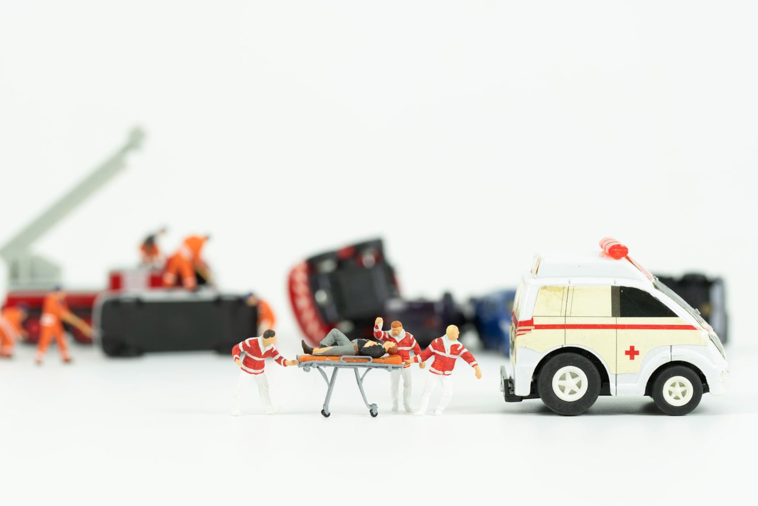 Miniature medical team carrying a person into an ambulance