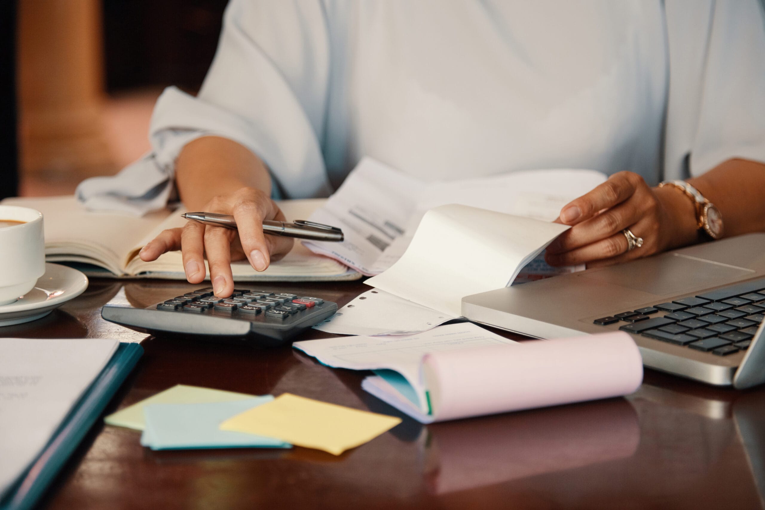 Person using a calculator and laptop while working on bills