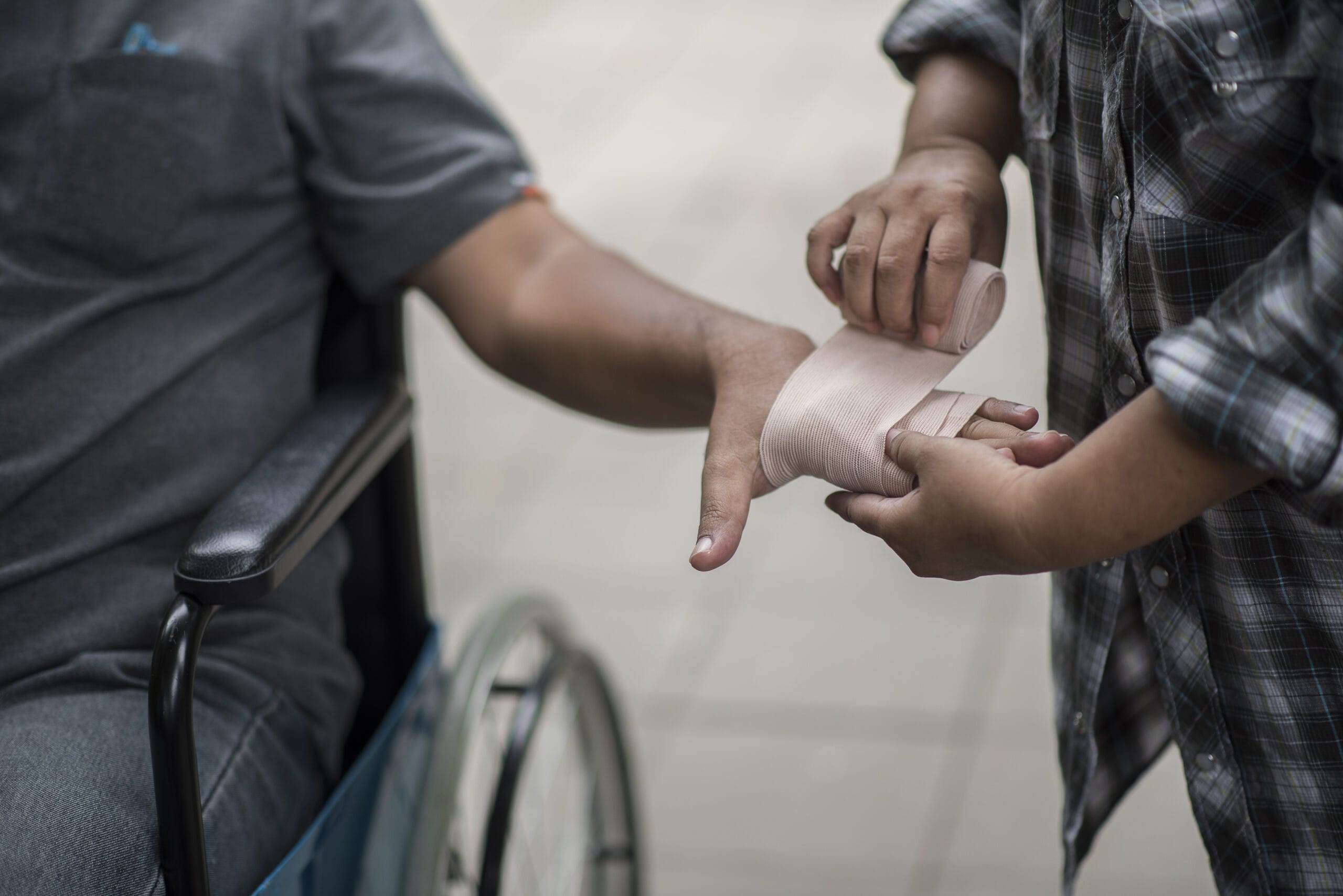 Person wrapping another's hand with bandages