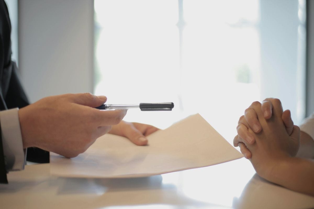 Business person handing another person papers and a pen