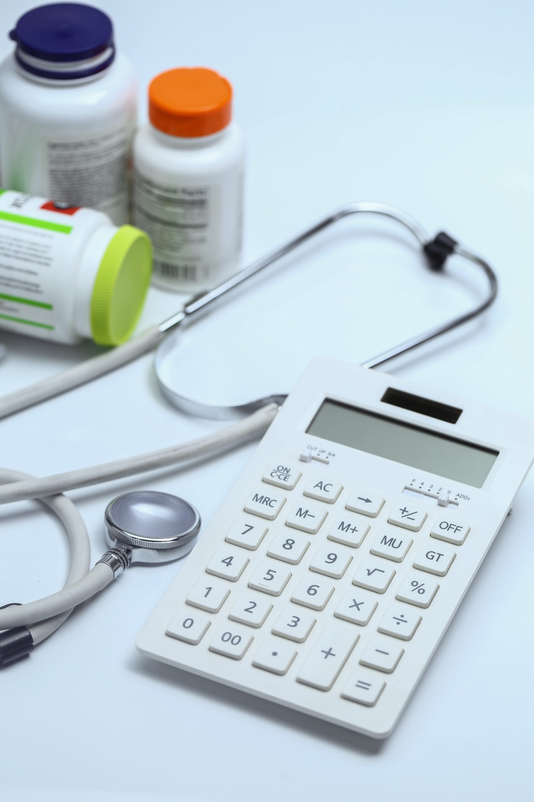 Calculator, stethoscope and bottles of medication