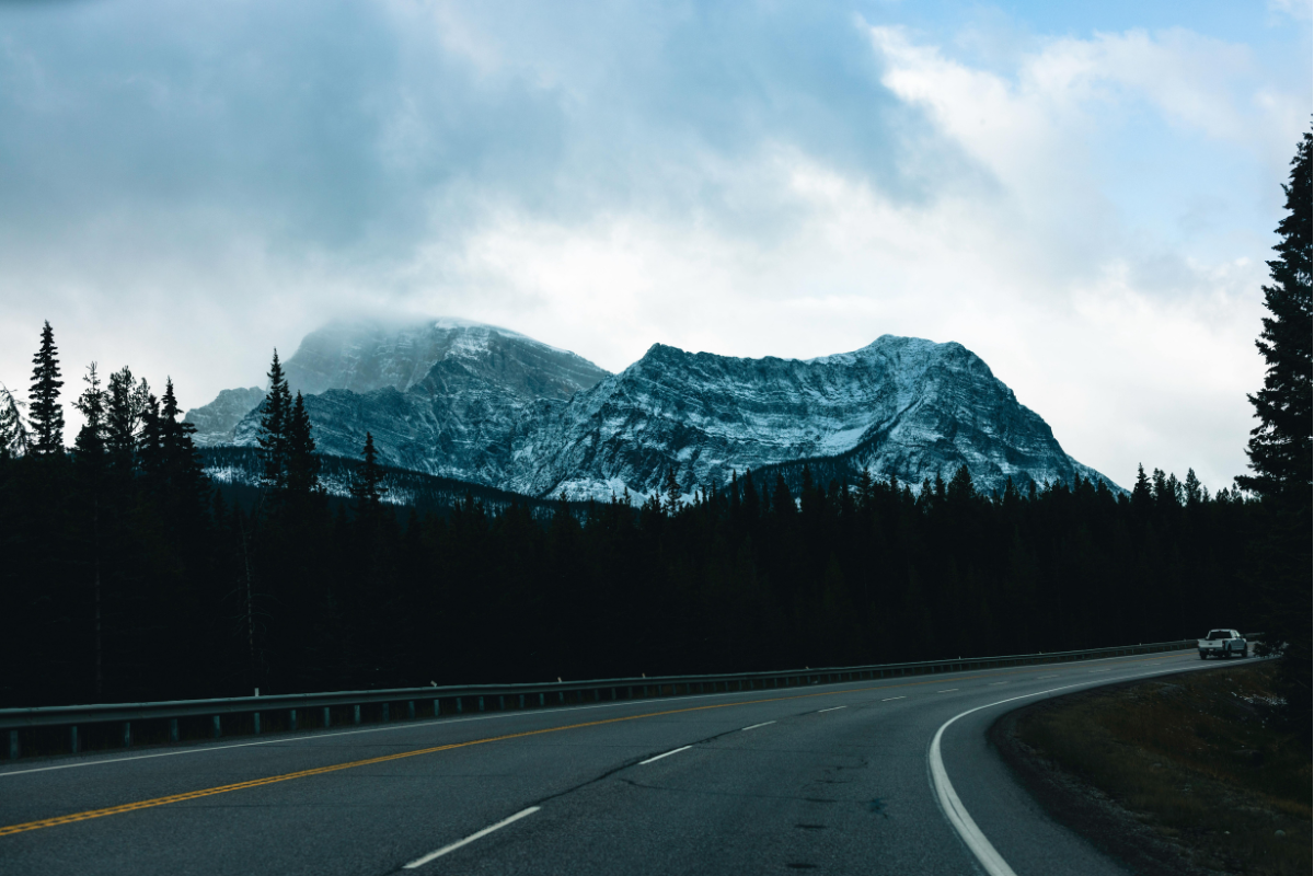 An Alberta road at dusk with mountains in the background