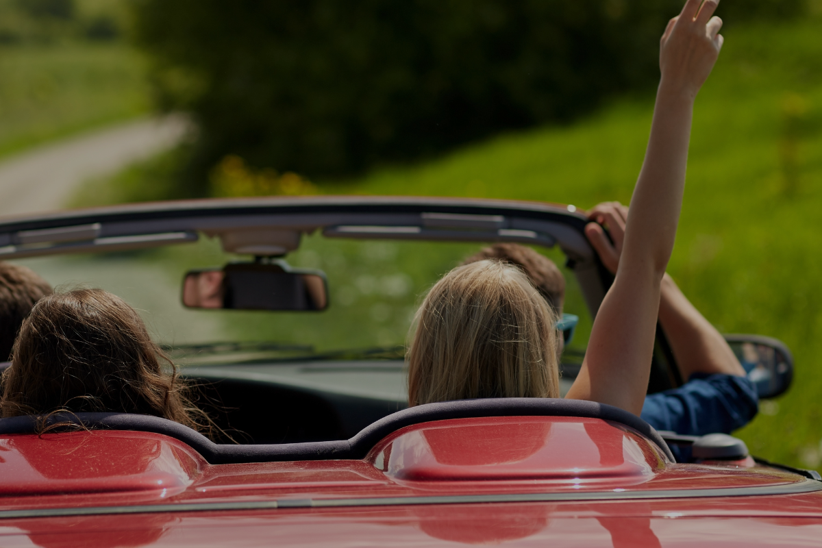 Four people driving in a convertible car