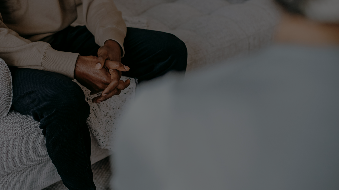 Person sitting on couch with hands together